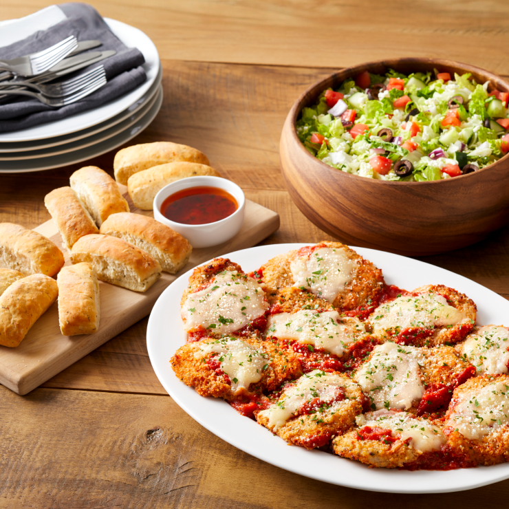 A platter of Chicken Parmasean with garlic bread and salad.