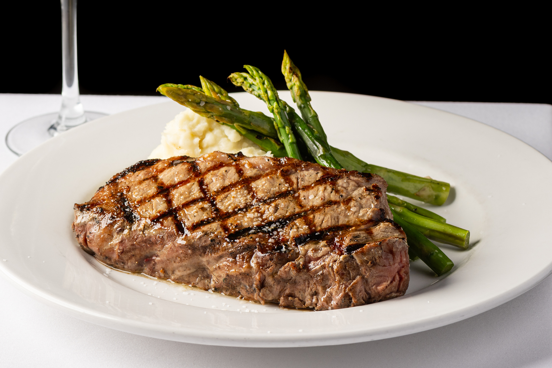 Grilled steak served with mashed potatoes and asparagus on a white plate at Bravo Italian Kitchen.